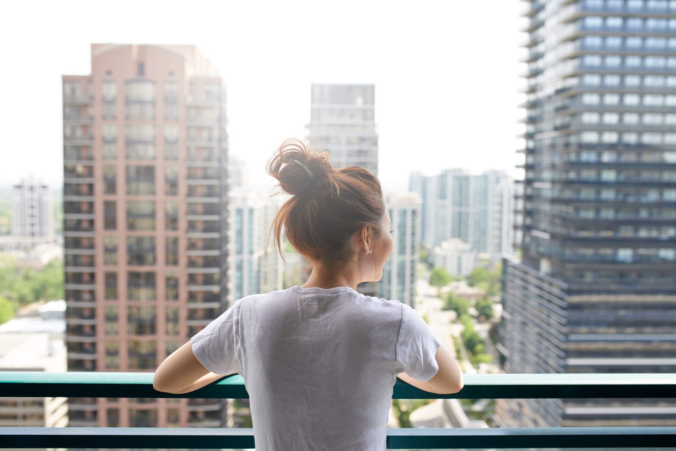 woman gazing at the cityscape from her balcony