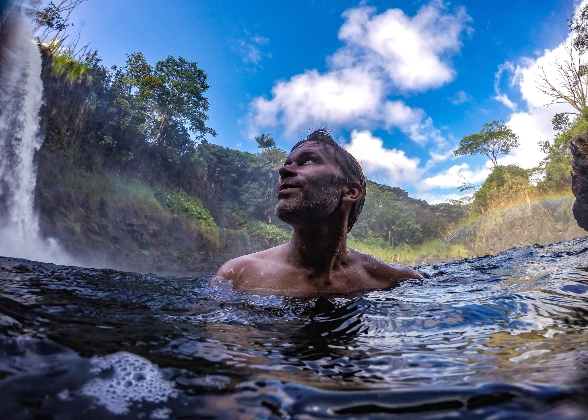 man under waterfall in Hawaii