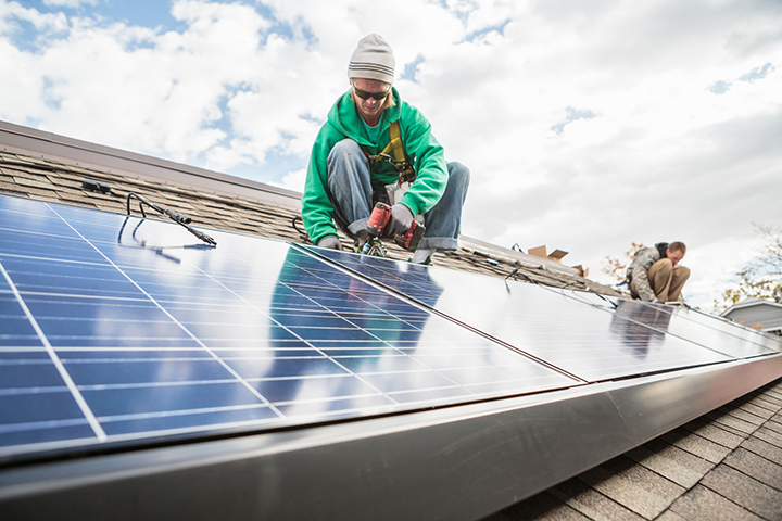 man with solar panels on a roof