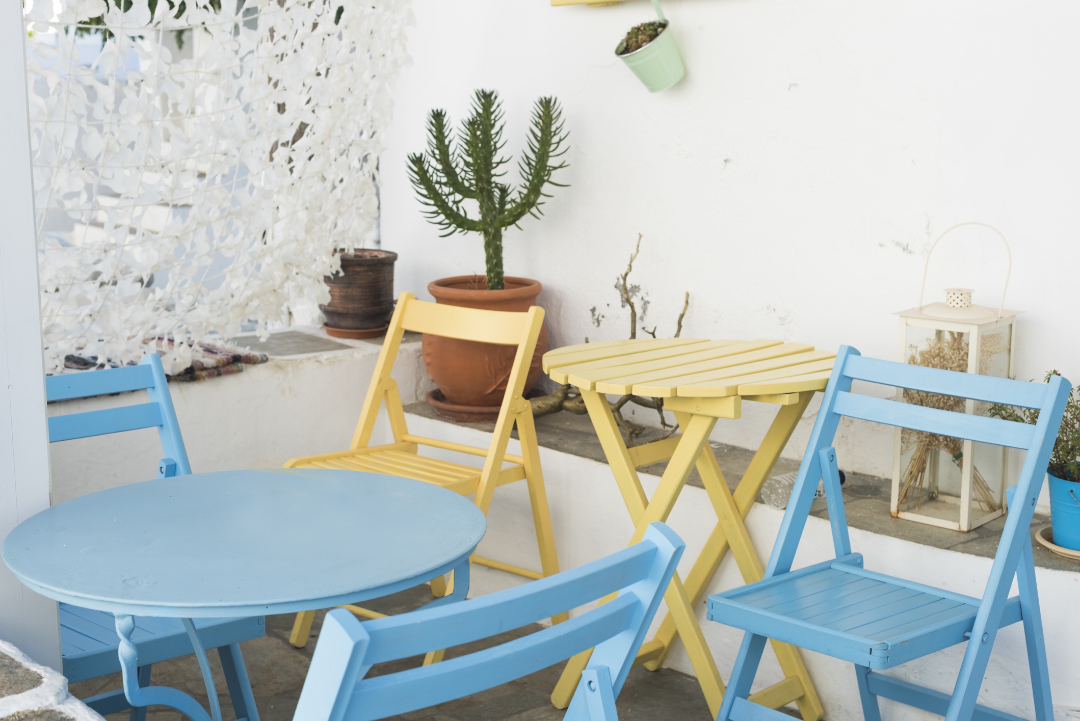 A white patio with bright blue and yellow chairs and tables