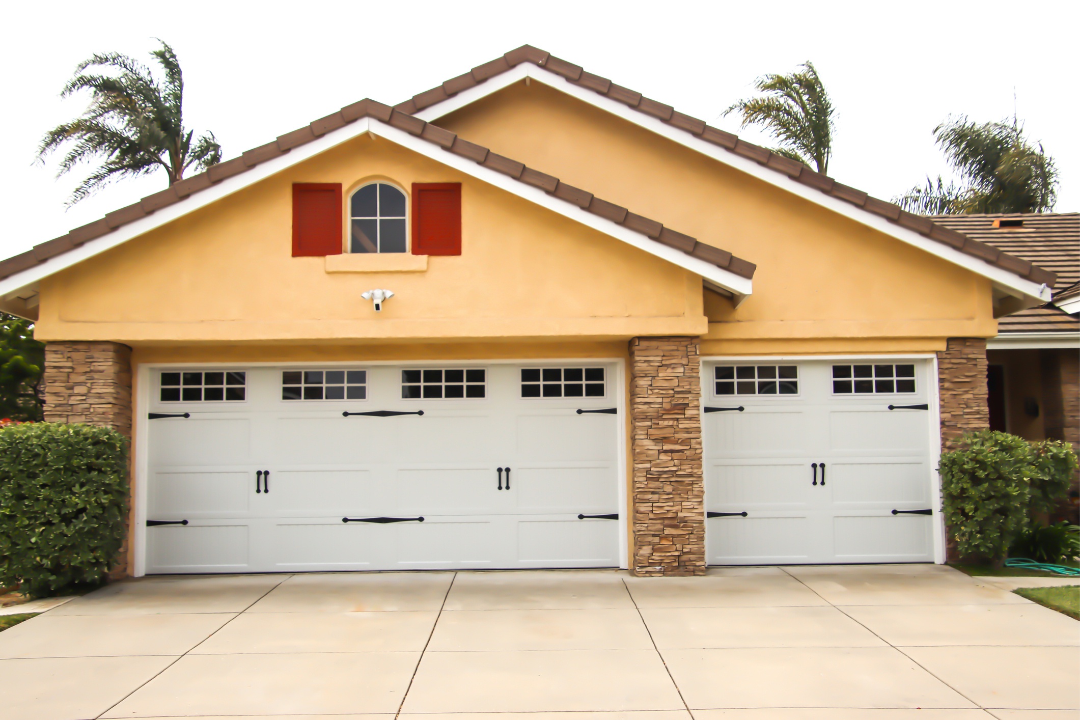 A double gabled yellow house with two white garage doors
