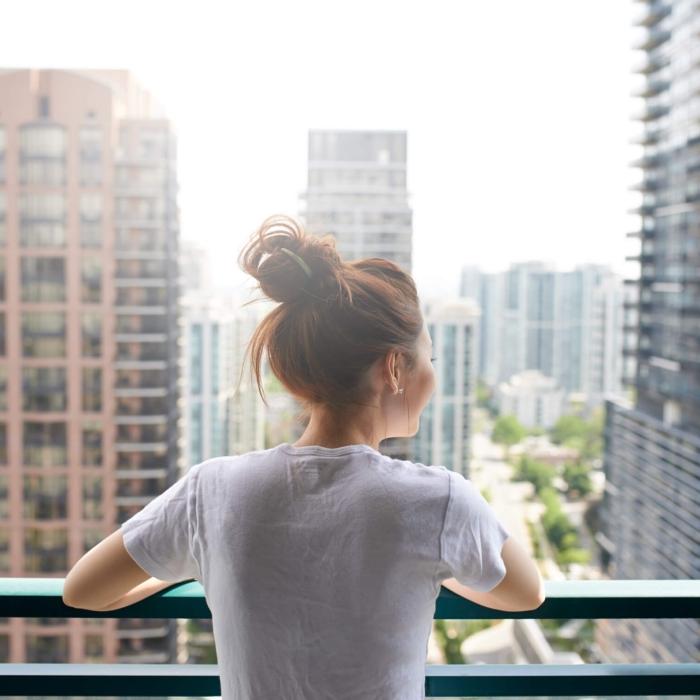woman gazing at the cityscape from her balcony